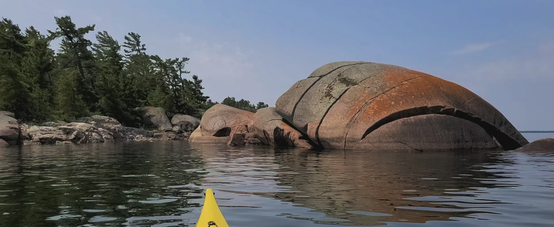 Western Shoreline of the Benjamind islands with red granite rock, white quartzite,
                trees and clear water